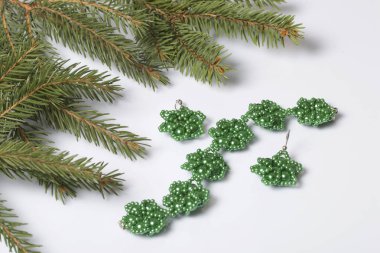 Kadın küpe ve ladin dallar arasında boncuklu bilezik. Beyaz bir arka plan üzerinde.