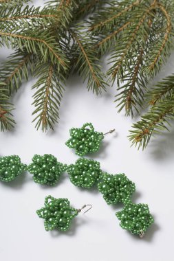 Kadın küpe ve ladin dallar arasında boncuklu bilezik. Beyaz bir arka plan üzerinde.