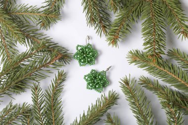 Kadın küpe boncuk Ladin dallar arasında yapılmış. Beyaz bir arka plan üzerinde.