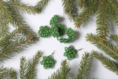 Kadın küpe ve ladin dallar arasında boncuklu bilezik. Beyaz bir arka plan üzerinde.