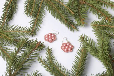 Kadın küpe boncuk Ladin dallar arasında yapılmış. Beyaz bir arka plan üzerinde.