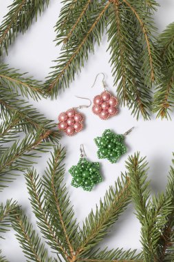 Kadın küpe boncuk Ladin dallar arasında yapılmış. Beyaz bir arka plan üzerinde.