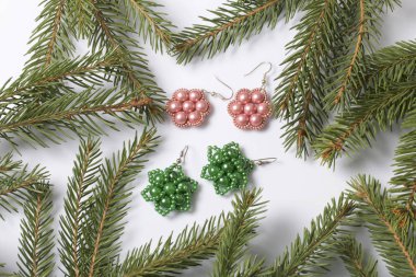 Kadın küpe boncuk Ladin dallar arasında yapılmış. Beyaz bir arka plan üzerinde.