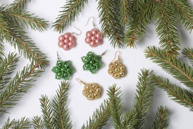 Kadın küpe boncuk Ladin dallar arasında yapılmış. Beyaz bir arka plan üzerinde.