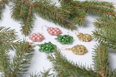 Kadın küpe boncuk Ladin dallar arasında yapılmış. Beyaz bir arka plan üzerinde.