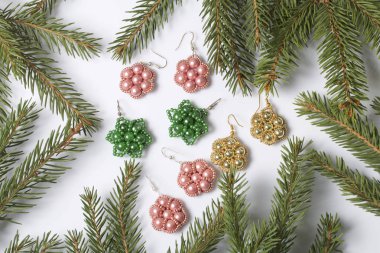 Kadın küpe boncuk Ladin dallar arasında yapılmış. Beyaz bir arka plan üzerinde.