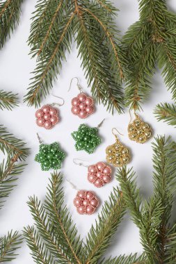 Kadın küpe boncuk Ladin dallar arasında yapılmış. Beyaz bir arka plan üzerinde.