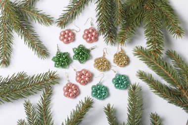 Kadın küpe ve ladin dallar arasında boncuklu bilezik. Beyaz bir arka plan üzerinde.