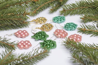 Kadın küpe ve ladin dallar arasında boncuklu bilezik. Beyaz bir arka plan üzerinde.