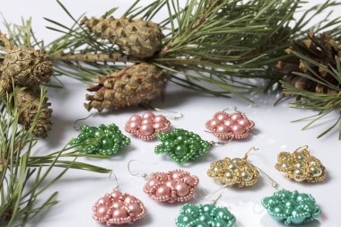 Kadın küpe boncuk koniler ile çam dalları arasında. Beyaz bir arka plan üzerinde.