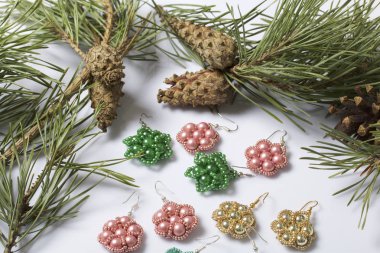 Kadın küpe boncuk koniler ile çam dalları arasında. Beyaz bir arka plan üzerinde.