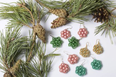 Kadın küpe boncuk koniler ile çam dalları arasında. Beyaz bir arka plan üzerinde.