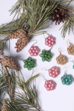 Kadın küpe boncuk koniler ile çam dalları arasında. Beyaz bir arka plan üzerinde.