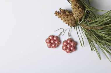 Kadın küpe boncuk koniler ile çam dalları arasında. Beyaz bir arka plan üzerinde.