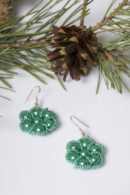 Kadın küpe boncuk koniler ile çam dalları arasında. Beyaz bir arka plan üzerinde.