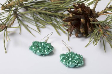 Kadın küpe boncuk koniler ile çam dalları arasında. Beyaz bir arka plan üzerinde.