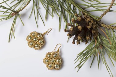 Kadın küpe boncuk koniler ile çam dalları arasında. Beyaz bir arka plan üzerinde.