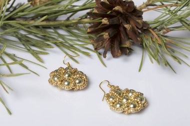 Kadın küpe boncuk koniler ile çam dalları arasında. Beyaz bir arka plan üzerinde.