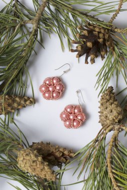 Kadın küpe boncuk koniler ile çam dalları arasında. Beyaz bir arka plan üzerinde.