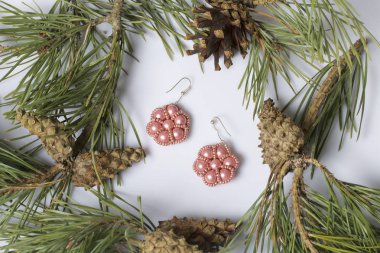 Kadın küpe boncuk koniler ile çam dalları arasında. Beyaz bir arka plan üzerinde.