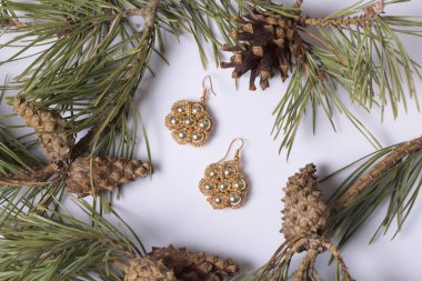 Kadın küpe boncuk koniler ile çam dalları arasında. Beyaz bir arka plan üzerinde.