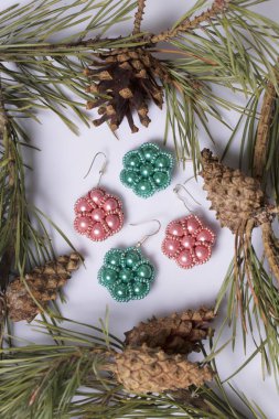 Kadın küpe boncuk koniler ile çam dalları arasında. Beyaz bir arka plan üzerinde.