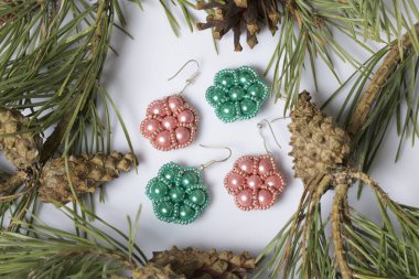 Kadın küpe boncuk koniler ile çam dalları arasında. Beyaz bir arka plan üzerinde.