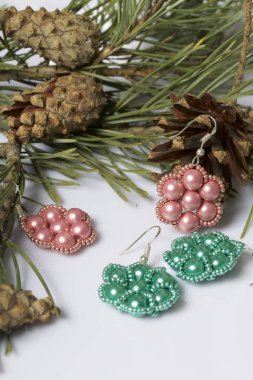 Kadın küpe boncuk koniler ile çam dalları arasında. Beyaz bir arka plan üzerinde.