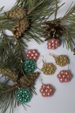 Kadın küpe boncuk koniler ile çam dalları arasında. Beyaz bir arka plan üzerinde.