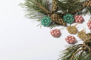 Kadın küpe boncuk koniler ile çam dalları arasında. Beyaz bir arka plan üzerinde.