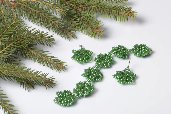 Kadın küpe ve ladin dallar arasında boncuklu bilezik. Beyaz bir arka plan üzerinde.