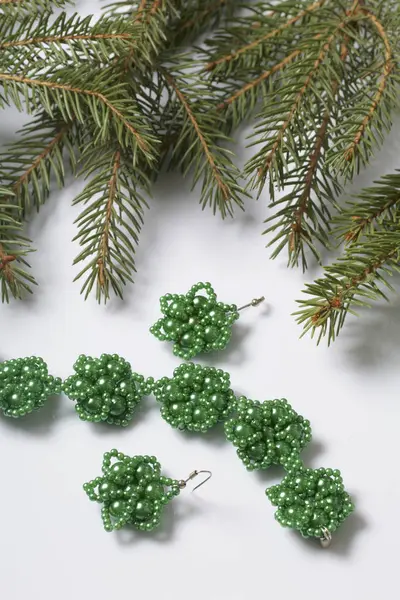 Kadın küpe ve ladin dallar arasında boncuklu bilezik. Beyaz bir arka plan üzerinde.