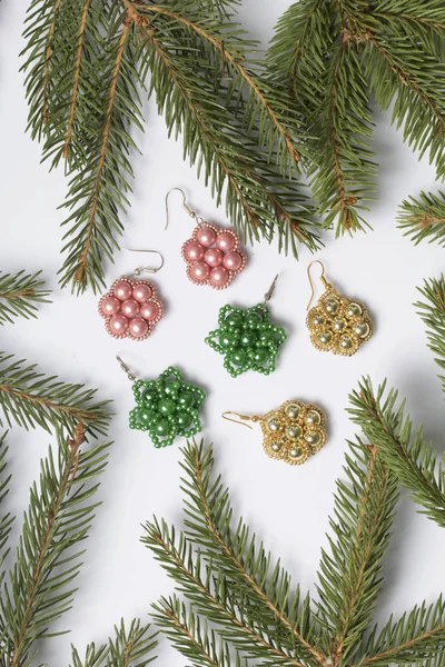 Kadın küpe boncuk Ladin dallar arasında yapılmış. Beyaz bir arka plan üzerinde.