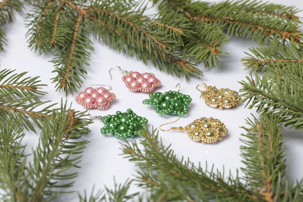 Kadın küpe boncuk Ladin dallar arasında yapılmış. Beyaz bir arka plan üzerinde.