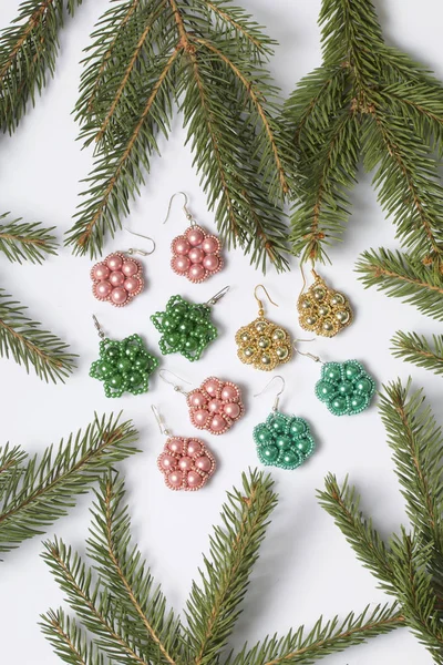 Kadın küpe boncuk Ladin dallar arasında yapılmış. Beyaz bir arka plan üzerinde.