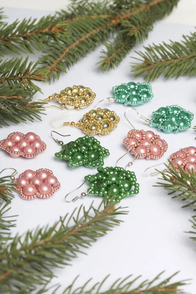 Kadın küpe ve ladin dallar arasında boncuklu bilezik. Beyaz bir arka plan üzerinde.