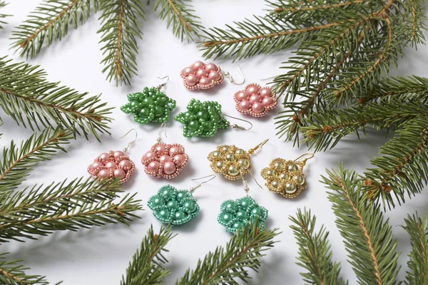 Kadın küpe boncuk Ladin dallar arasında yapılmış. Beyaz bir arka plan üzerinde.