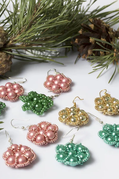 Kadın küpe boncuk koniler ile çam dalları arasında. Beyaz bir arka plan üzerinde.