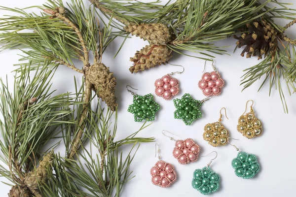 Kadın küpe boncuk koniler ile çam dalları arasında. Beyaz bir arka plan üzerinde.