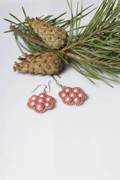 Kadın küpe boncuk koniler ile çam dalları arasında. Beyaz bir arka plan üzerinde.