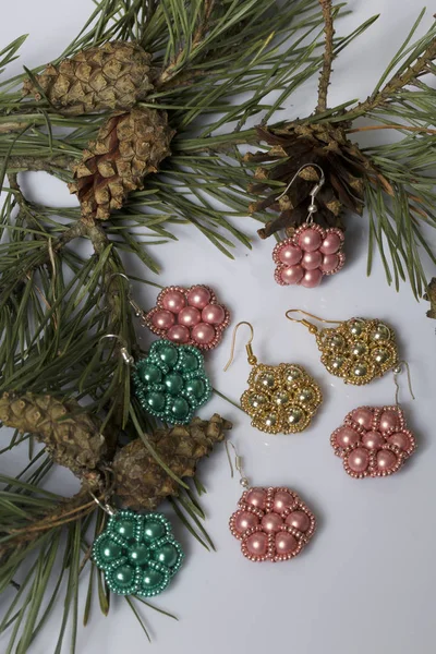 Kadın küpe boncuk koniler ile çam dalları arasında. Beyaz bir arka plan üzerinde.