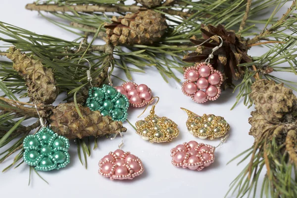 Kadın küpe boncuk koniler ile çam dalları arasında. Beyaz bir arka plan üzerinde.