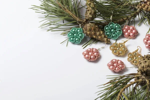 Kadın küpe boncuk koniler ile çam dalları arasında. Beyaz bir arka plan üzerinde.