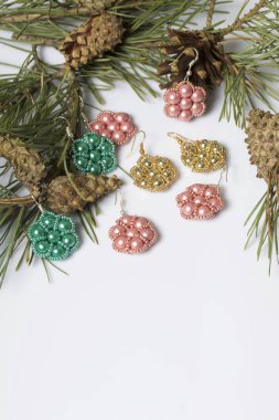 Kadın küpe boncuk koniler ile çam dalları arasında. Beyaz bir arka plan üzerinde.