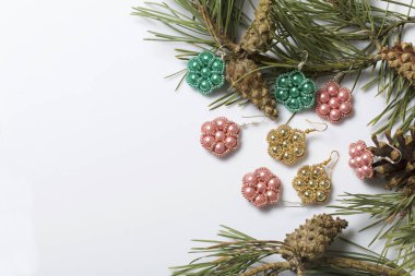 Kadın küpe boncuk koniler ile çam dalları arasında. Beyaz bir arka plan üzerinde.