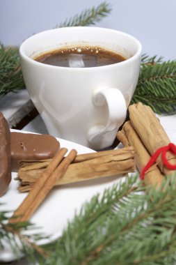 Bir fincan kahve, tarçın ve çam dalları yanında çikolata. Bir ahşap kutu.