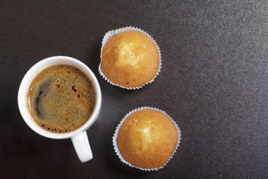 Bir bardak taze demlenmiş kahve ve çörek. Karanlık bir arka plan üzerinde.