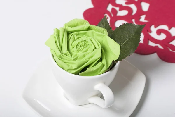 Preparation of floral decorations using napkins and table forks. The finished flower is placed in a cup and decorated with green leaves.