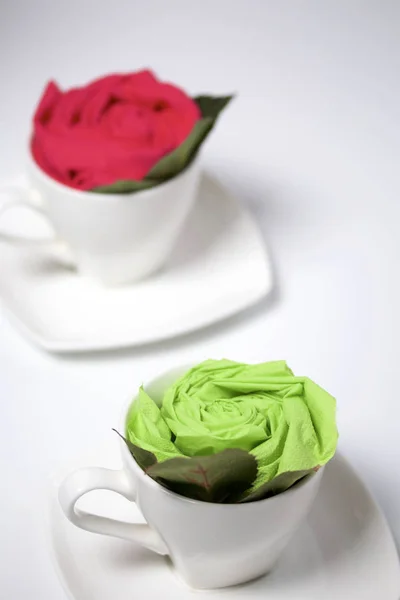Preparation of floral decorations using napkins and table forks. The finished flower is placed in a cup and decorated with green leaves.