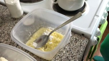 Bir kadın Vanilin ve eritilmiş tereyağı krema şeker bir kapsayıcıya ekler. Tatlı için malzemeler.